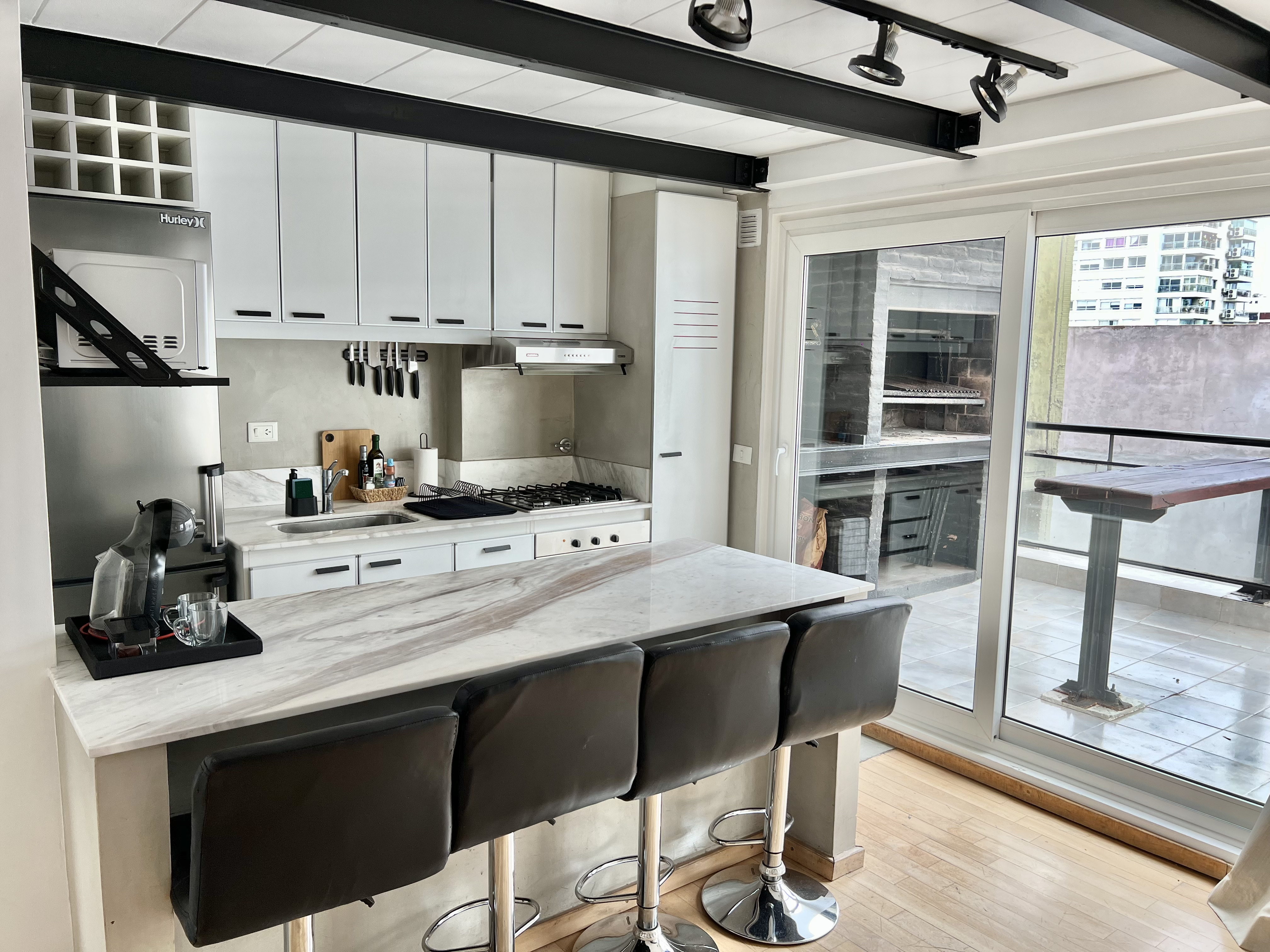 Cocina con isla de mármol y acceso a terraza